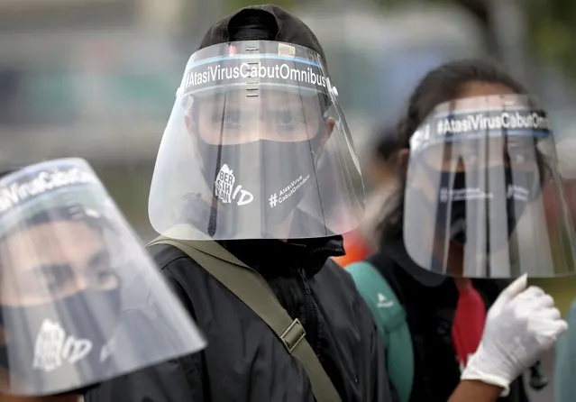 Activists wearing protective face shields as a precaution against the new coronavirus outbreak attend a small protest outside the parliament in Jakarta, Indonesia, Tuesday, July 14, 2020. About a dozen activists staged the protest opposing the government's omnibus bill on job creation that was intended to boost economic growth and create jobs, saying that it undermined labor rights and environmental protection. (Photo by Dita Alangkara/AP Photo)