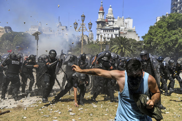Riot police clash with demonstrators protesting against proposed pension reforms outside the Congress in Buenos Aires on December 18, 2017. Protesters angry at proposed pension and welfare reforms attacked police close to Argentina's congress building in Buenos Aires on Monday, the second protest in a week to turn violent. Activists lobbed stones, bottles and firecrackers at police as huge crowds demonstrated against pension reforms proposed by the center-right government of President Mauricio Macri. (Photo by Eitan Abramovich/AFP Photo)