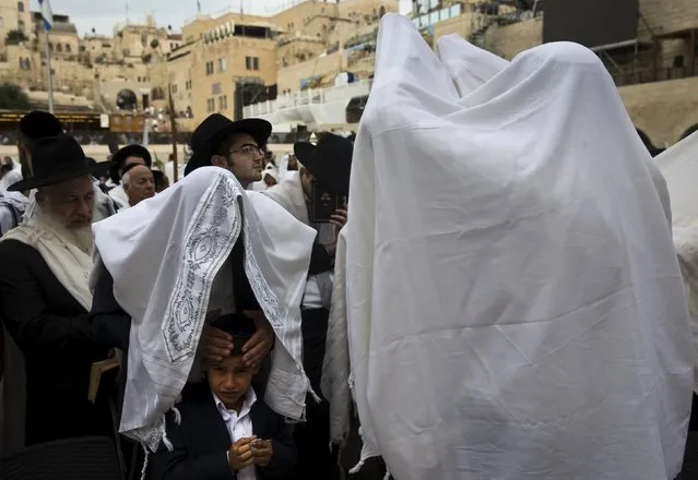 Jewish worshippers cover themselves in prayer shawls as they recite the priestly blessing at the Western Wall in Jerusalem's Old City during the holiday of Sukkot September 30, 2015. (Photo by Ronen Zvulun/Reuters)