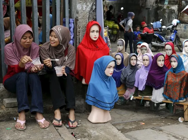 Girls sit near mannequins displaying hijabs for sale at Tanah Abang market, ahead of the holy fasting month of Ramadan, in Jakarta in this June 27, 2014 file photo. Indonesia is expected to release data on inflation this week.