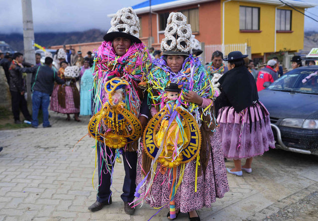 Carnival party hosts, Eddy Carrasco and wife Juana Vallejo, wearing hats made of sweet bread that represent hope against hunger in the coming year, pose for a photo during a “Martes de Challa”, or Challa Tuesday event, a Carnival celebration that gives thanks to the “Pachamama” or Mother Earth, in Achocalla, Bolivia, Tuesday, February 13, 2024. (Photo by Juan Karita/AP Photo)