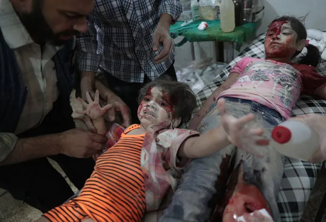 A Syrian girl reacts in pain as a wounded child lies next to her at a make-shift hospital following reported government air strikes on the rebel-held town of Douma, east of the capital Damascus on September 12, 2016. A new ceasefire brokered by Russia and the United States is due to begin at sundown on September 12, 2016, in Syria. It aims to halt fighting between President Bashar al-Assad's forces and the opposition, but does not apply to jihadists like the Islamic State group. (Photo by Abd Doumany/AFP Photo)