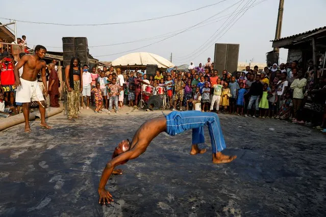 Children watch a dancer perform during an annual slum party in Oworonshoki, Lagos, Nigeria on December 23, 2022. (Photo by Temilade Adelaja/Reuters)