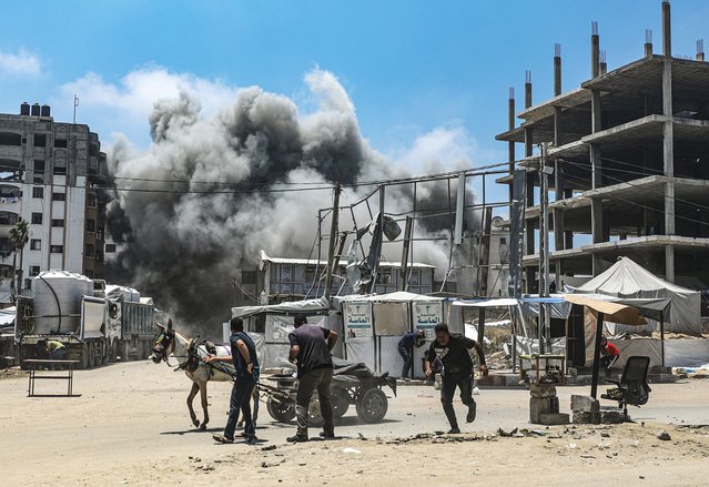 Palestinians try to take cover as smoke rises following an Israeli airstrike west of Gaza City, in Gaza Strip, 23 May 2025. More than 53,700 Palestinians have been killed in the Gaza Strip, according to the Palestinian Ministry of Health, since Israel launched a military campaign in the strip in response to a cross-border attack led by the Palestinian militant group Hamas on 07 October 2023, in which about 1,200 Israelis were killed and more than 250 taken hostage. (Photo by Mohammed Saber/EPA/EFE)