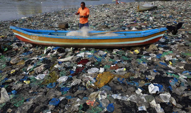 A fisherman prepares his net on the shores of the Arabian Sea, littered with plastic bags, in Mumbai, India, Thursday, Oct0ber 1, 2015. Thursday marks one year since Indian Prime Minister Narendra Modi launched the "Swachh Bharat Abhiyaan" or "Clean India Mission." (Photo by Rafiq Maqbool/AP Photo)