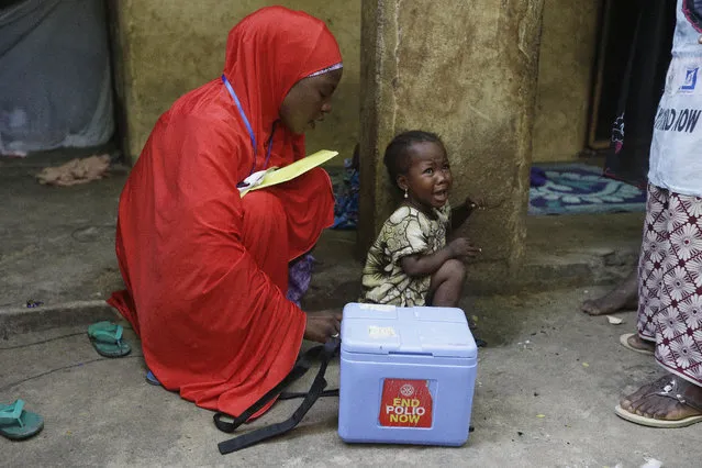 In this photo taken on Saturday, August 28, 2016, a child cries after she was administered with a polio vaccine during a house to house vaccination exercise in Maiduguri, Nigeria. An emergency polio vaccination campaign aimed at reaching 25 million children this year has begun in parts of Nigeria newly freed from Boko Haram Islamic extremists, with fears that many more cases of the crippling disease are likely to be found. (Photo by Sunday Alamba/AP Photo)