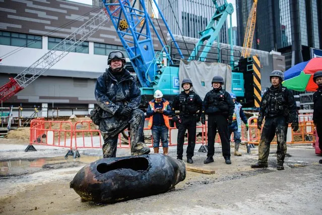 Bomb disposal expert Adam Roberts (L) rests his foot on a defused US-made bomb dropped during World War II a day after it was discovered on a harbourfront construction site in the Wan Chai district of Hong Kong on February 1, 2018. A wartime bomb was defused in Hong Kong on February 1 after a busy commercial district went into lockdown, with roads closed and thousands evacuated from surrounding shops, hotels and offices. (Photo by Anthony Wallace/AFP Photo)