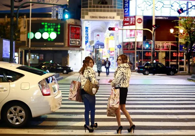 Women carry shopping bags in the Dotonbori amusement district of Osaka, western Japan November 19, 2014. (Photo by Thomas Peter/Reuters)