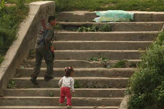 A soldier and a child walk up steps at the bank of the Yalu River, outside the North Korean town of Sinuiju, opposite Dandong in China's Liaoning province, September 11, 2016. (Photo by Thomas Peter/Reuters)