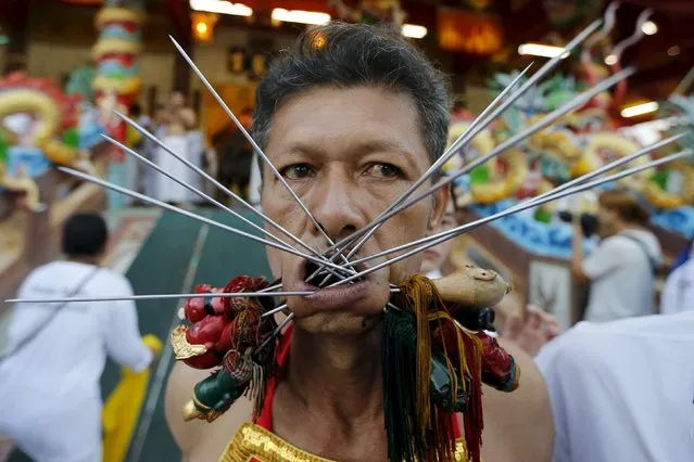 A devotee of the Chinese Ban Tha Rue shrine walks with spikes pierced through his cheeks during a procession celebrating the annual vegetarian festival in Phuket, Thailand, October 17, 2015. (Photo by Jorge Silva/Reuters)