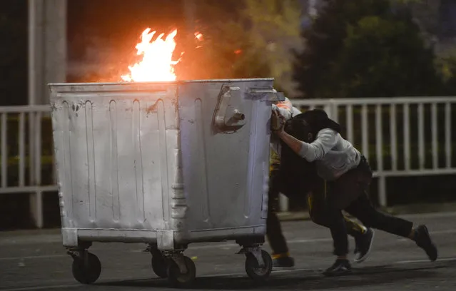 Protesters push a burning trash can towards riot police during a rally against the results of a parliamentary vote in Bishkek, Kyrgyzstan, Monday, October 5, 2020. (Photo by Vladimir Voronin/AP Photo)