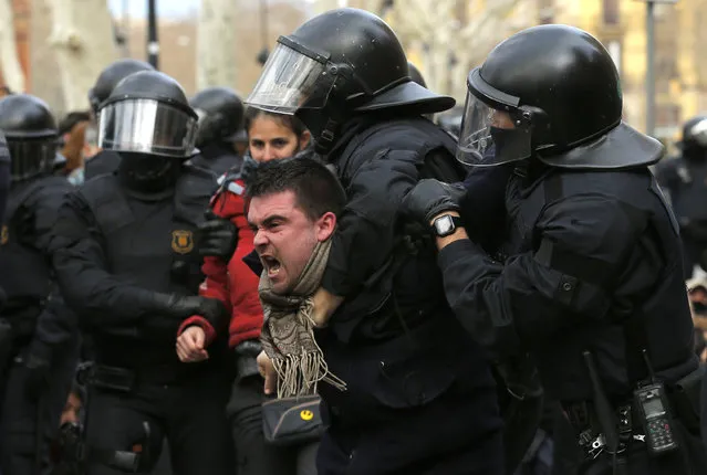 Catalan Mossos d'Esquadra officers carry a protestor as they block TSJC (Superior Court of Justice of Catalonia) during a protest called by the 'Commitees in defence of the Republic' in Barcelona, Spain, Friday, February 23, 2018. Former regional Vice President Oriol Junqueras, and activists Jordi Sanchez and Jordi Cuixart face possible sedition charges. Junqueras is also investigated for alleged rebellion and embezzlement, punishable with decades in prison. (Photo by Manu Fernandez/AP Photo)