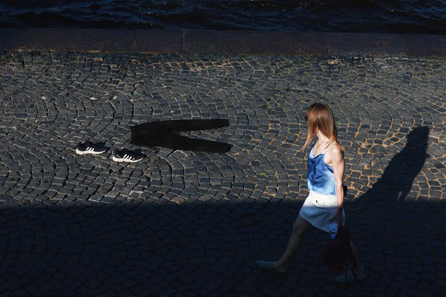 A woman walks past clothes laid out to dry during a hot day in Saint Petersburg, Russia, on July 15, 2025. (Photo by Anton Vaganov/Reuters)