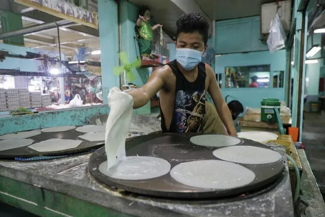 Mark Fulgencio cooks spring roll wrappers at a market in Quezon city, Philippines, Saturday September 26, 2020. Government orders people in public areas to wear face masks to help curb the spread of the coronavirus. (Photo by Aaron Favila/AP Photo)