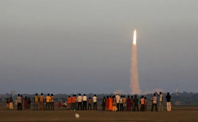 Onlookers watch as the Indian Space Research Organization’s Polar Satellite Launch Vehicle (PSLV-C20) lifts off from the Satish Dhawan Space Center in Sriharikota, India, on February 25, 2013. The rocket successfully launched the SARAL oceanographic satellite and six other spacecraft. (Photo by Arun Sankar K./AP Photo)