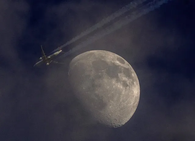 An aircraft passes the moon that is slightly covered Wirth clouds in Frankfurt, Germany, Wednesday, late May 11, 2022. (Photo by Michael Probst/AP Photo)