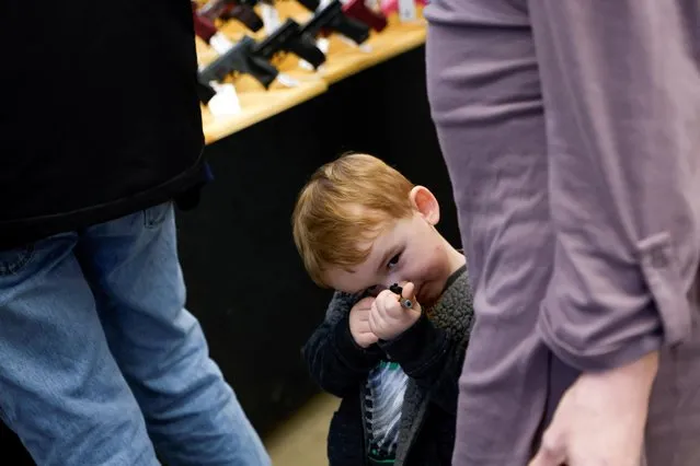 Westley Owens, 3, plays with a small toy gun as he accompanies his mother attending the Des Moines Fairgrounds Gun Show at the Iowa State Fairgrounds in Des Moines, Iowa, U.S. March 11, 2023. (Photo by Jonathan Ernst/Reuters)