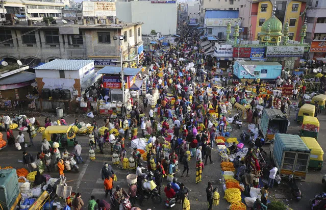Shoppers crowd at a wholesale flower market in Bengaluru, India, Friday, November 20, 2020. India's total number of coronavirus cases since the pandemic began has crossed 9 million. Nevertheless the country's new daily cases have seen a steady decline for weeks now. (Photo by Aijaz Rahi/AP Photo)