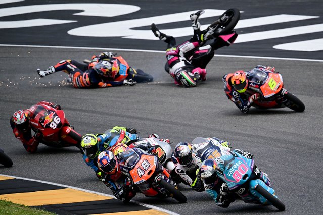 Spain's Red Bull KTM Ajo rider Jose Antonio Rueda (L) and Italy's MTA Team rider Stefano Nepa crash as Colombia's CFMOTO Aspar Team rider #80 David Alonso leads the pack during the Italian Moto 3 race at Mugello on June 2, 2024. (Photo by Marco Bertorello/AFP Photo)