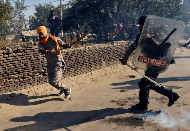 A policeman chases away a farmer during a protest against the newly passed farm bills at Singhu border near Delhi, India, November 27, 2020. (Photo by Danish Siddiqui/Reuters)