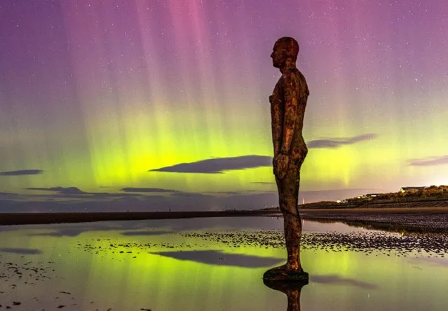 A statue by Antony Gormley is seen with the northern lights at Crosby Beach, north of Liverpool, United Kingdom on February 26, 2023. (Photo by Dominic Darvell/Picture Exclusive)