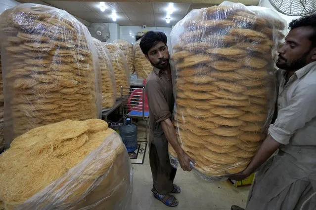 Workers carry vermicelli, a special delicacy prepared for the upcoming Muslim fasting month of Ramadan, in Karachi, Pakistan, Tuesday, March 21, 2023. (Photo by Fareed Khan/AP Photo)