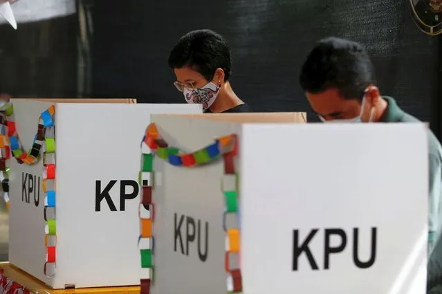 Voters wearing protective masks mark their ballots at a polling booth during regional elections in Tangerang, near Jakarta, Indonesia, December 9, 2020. (Photo by Willy Kurniawan/Reuters)