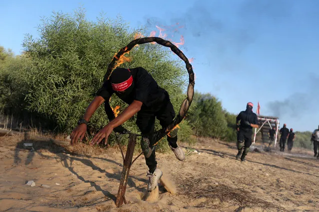 A Palestinian militant of the National Resistance brigades, the armed wing of the Democratic Front for the Liberation of Palestine (DFLP), jumps through a ring of fire during a graduation ceremony in Rafah in the southern Gaza Strip October 28, 2016. (Photo by Ibraheem Abu Mustafa/Reuters)