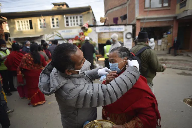 A volunteer to helps to put masks on devotees face during Saat Gaule Jatra at Panga, Kirtipur, Kathmandu, Nepal on Wednesday, December 23, 2020. It is the part of famous festival celebrated annually marking the arrival of winter. Jatras and festivals are part of life for Newar community. (Photo by Narayan Maharjan/NurPhoto via Getty Images)