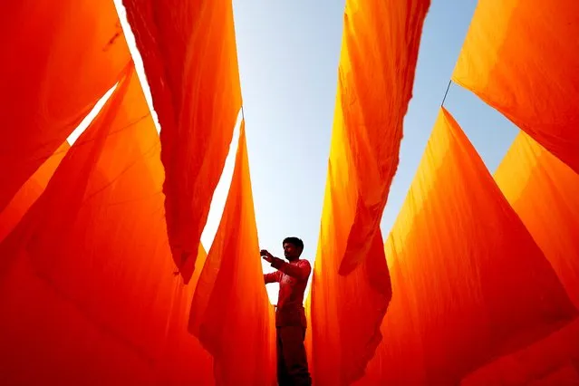 A worker dries fabrics after applying color at a dye factory in Narayanganj, Bangladesh, January 13, 2021. (Photo by Mohammad Ponir Hossain/Reuters)