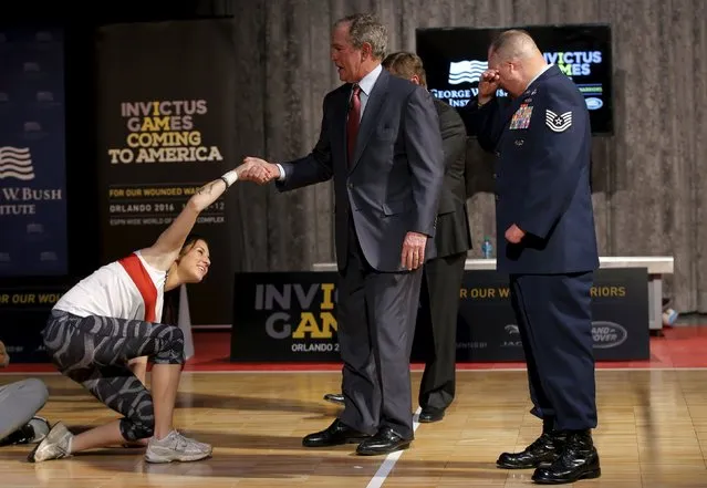 Former U.S. President George W. Bush helps wounded veteran Kristen Esget, U.S. Coast Guard Yeoman 3rd Class, to her feet before a demonstration of sitting volleyball while meeting wounded veteran competitors who are training for the Invictus Games Orlando 2016 at the Intrepid Sea, Air & Space Museum in New York, December 3, 2015. The Invictus Games will bring together more than 500 competitors from 15 nations to compete in 10 sports. At right is U.S. Air Force Technical Sergeant Israel Del Toro. (Photo by Mike Segar/Reuters)