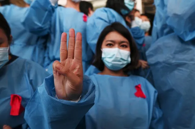 Medical staff make a three finger salute with red ribbons on their uniform at the Yangon General Hospital in Yangon on February 3, 2021 as calls for a civil disobedience gather pace following a military coup detaining civilian leader Aung San Suu Kyi. (Photo by Reuters/Stringer)