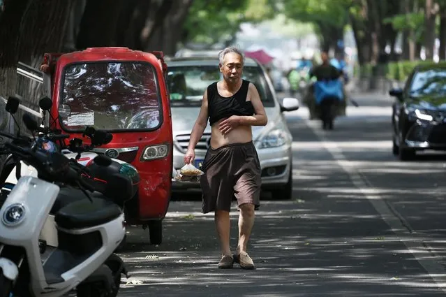 A man walks on a street during a heatwave in Beijing on June 23, 2023. (Photo by Greg Baker/AFP Photo)