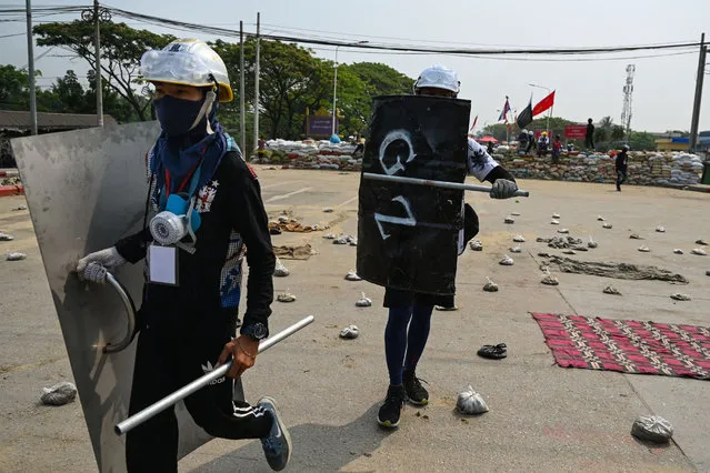 Protesters hold homemade shields as they walk through an area with makeshift barricades to deter security forces during demonstrations against the military coup in Yangon on March 14, 2021. (Photo by AFP Photo/Stringer)