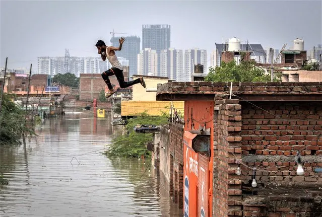 A man jumps into the flood waters at a flooded colony, after a rise in the water level of the river Yamuna due to heavy monsoon rains, in New Delhi, India on July 14, 2023. (Photo by Adnan Abidi/Reuters)