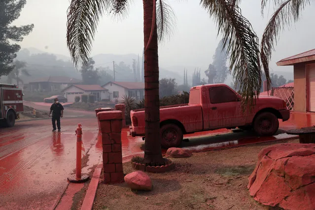 A truck and a street are covered in fire retardant dropped by an air tanker as crews battle a wildfire Friday, August 10, 2018, in Lake Elsinore, Calif. (Photo by Marcio Jose Sanchez/AP Photo)