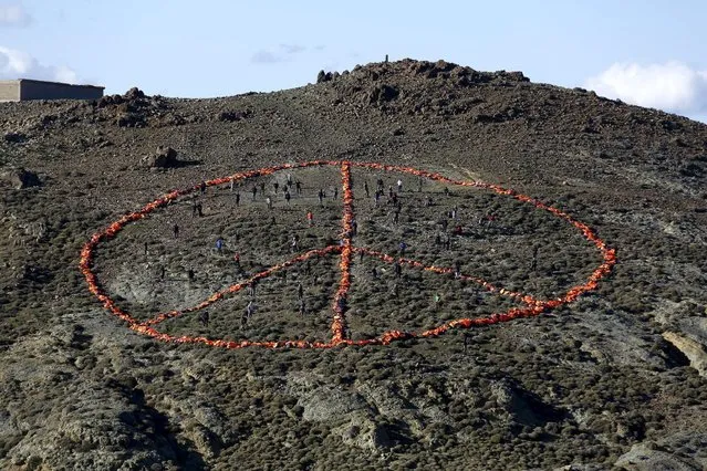 Volunteers from various non-governmental organizations (NGO) arrange more than 2,500 discarded lifejackets, used by refugees and migrants, in the shape of the peace symbol on the Greek island of Lesbos, January 1, 2016. (Photo by Giorgos Moutafis/Reuters)
