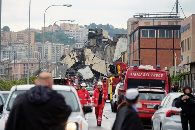 A picture taken on August 14, 2018 in Genoa shows a section of a giant motorway bridge that collapsed earlier injuring several people. Rescuers scouring through the wreckage after part of a viaduct of the A10 freeway collapsed said there were “tens of victims”, while images from the scene showed an entire carriageway plunged on to railway lines below. (Photo by Andrea Leoni/AFP Photo)