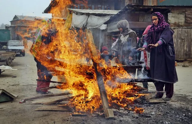 In this Tuesday, January 13, 2015 photo, Indian Kashmiri women warm their hands near a fire on a cold day in Srinagar, India. Cold wave conditions continued unabated in Kashmir Valley with widespread snowfall in the hilly areas. (Photo by Mukhtar Khan/AP Photo)
