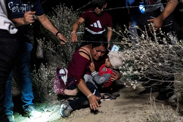 Asylum-seeking migrants' families go under a barbed wire fence while being escorted by a local church group to the location where they turn themselves in to the U.S. Border Patrol, after crossing the Rio Grande river into the United States from Mexico, in Roma, Texas, U.S. April 16, 2021. (Photo by Go Nakamura/Reuters)