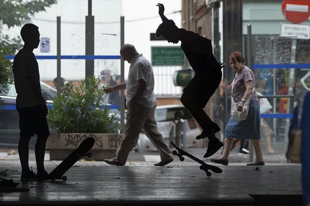 Youths practice with their skateboards in an alley as passers-by go about their business in a working class district of Madrid, Spain, Thursday, July 7, 2016. (Photo by Paul White/AP Photo)