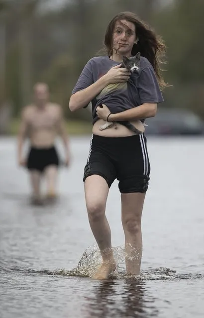 Amanda Mason carries a cat she rescued from her neighborhood off of Nine Foot Road, Sunday, September 16, 2018, in Newport, N.C. Mason and her partner Zack McWilliams visited their damaged home and found the displaced cat and carried it out to safety. Their home was flooded by fast rising water from a tributary of the Newport River on Friday night. (Photo by Robert Willett/The News & Observer via AP Photo)