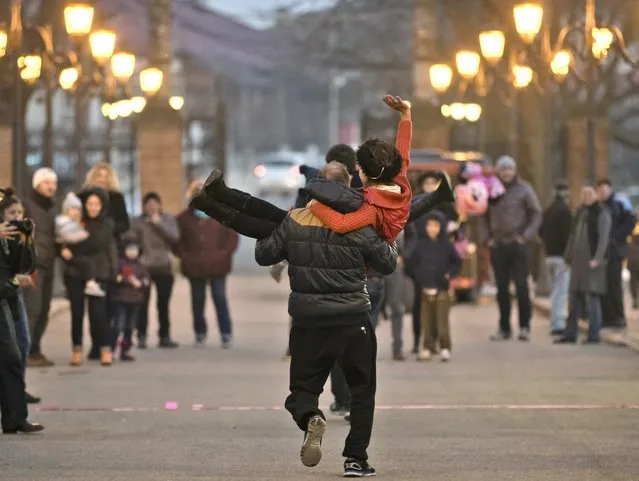A woman waves as her partner carries her while racing during a Valentine's Day event in Mogosoaia, Romania, Saturday, February 14, 2015. Never celebrated before the 1989 fall of the communist rule in Romania, Valentine's Day became ever more popular in the following years. And it is now widely adopted by Romanian youngsters. (Photo by Vadim Ghirda/AP Photo)