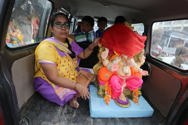 A devotee transports an idol of the Hindu god Ganesh, the deity of prosperity, in a taxi to a place of worship on the first day of the ten-day-long Ganesh Chaturthi festival, in Ahmedabad, India, September 13, 2018. (Photo by Amit Dave/Reuters)
