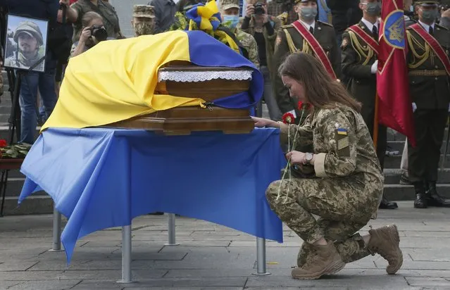 In this July 14, 2020, file photo, a Ukrainian soldier pays her final respects at the coffin of serviceman Taras Matviiv, honored with the Hero of Ukraine highest state award after being killed while fighting against pro-Russian rebels, during his funeral in Independence Square, Kyiv, Ukraine. Tensions have risen in the conflict in eastern Ukraine, with growing violations of a cease-fire and a massive Russian military buildup on its side of the border. (Photo by Efrem Lukatsky/AP Photo/File)