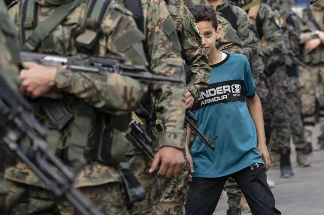 A child weaves between columns of Hamas militants as they parade through the streets for Bassem Issa, a top Hamas' commander, who was killed by Israeli Defense Force military actions prior to a cease-fire reached after an 11-day war between Gaza's Hamas rulers and Israel, in Gaza City, Saturday, May 22, 2021. (Photo by John Minchillo/AP Photo)