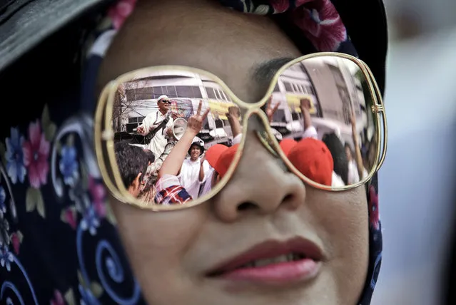 People taking part in a protest to support Jakarta Governor Basuki Tjahaja Purnama, popularly known as “Ahok”, is reflected in the sunglasses of a woman outside North Jakarta District Court where his trial is held, in Jakarta, Indonesia, Tuesday, December 13, 2016. Ahok is on trial on accusation of blasphemy following his remark about a passage in the Quran that could be interpreted as prohibiting Muslims from accepting non-Muslims as leaders. (Photo by Achmad Ibrahim/AP Photo)