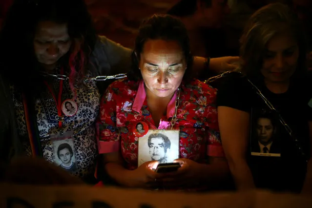 Relatives of victims of human rights abuses during the former dictatorship of Augusto Pinochet chain themselves to pews at the Cathedral of Santiago to protest against a mass taking place in the special prison for human rights abusers called “Punta Peuco”, acccording to local media, in Santiago, Chile December 22, 2016. (Photo by Ivan Alvarado/Reuters)