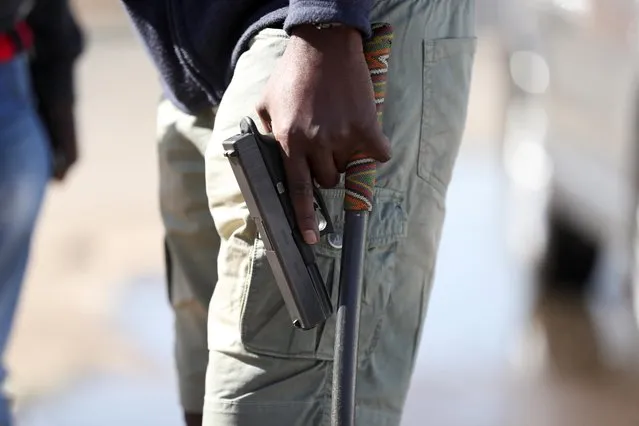 A man holds a pistol as the country deploys army to quell unrest linked to the jailing of former South African President Jacob Zuma, in Vosloorus, South Africa, July 14, 2021. (Photo by Siphiwe Sibeko/Reuters)