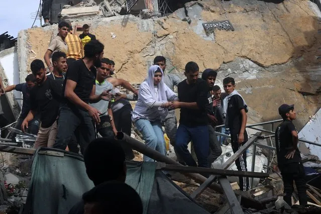 A woman is helped down from a building destroyed during Israeli bombing on Rafah in the southern Gaza Strip, on November 11, 2023, as battles between Israel and the Palestinian Hamas movement continue. (Photo by Said Khatib/AFP Photo)